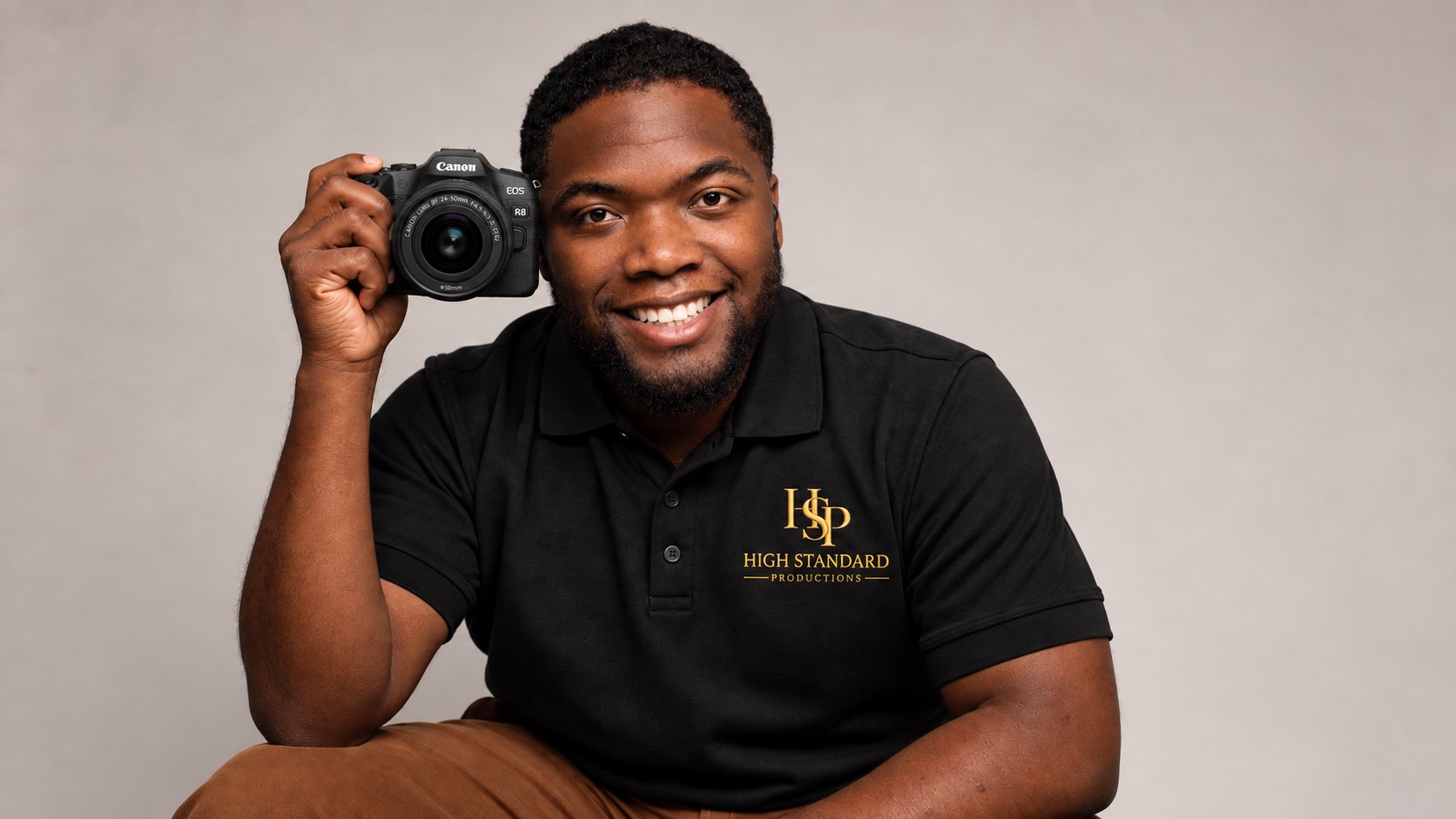 Devonnte Moody smiling with a Canon camera in a High Standard Productions polo